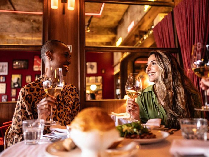 Archivo - Young friends toasting during dinner in the restaurant