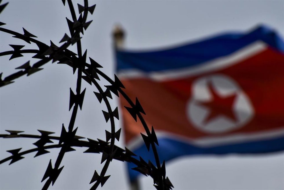 Archivo - Una bandera de Corea del Norte ondea tras una concertina