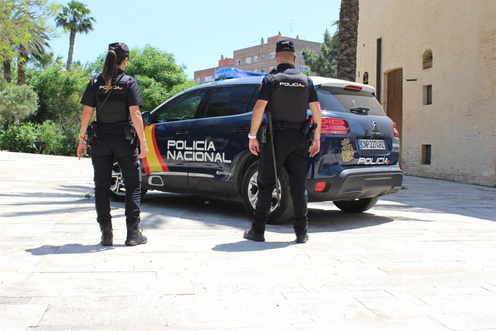 Archivo - Agentes de la Policía Nacional junto a un vehículo oficiaL.
