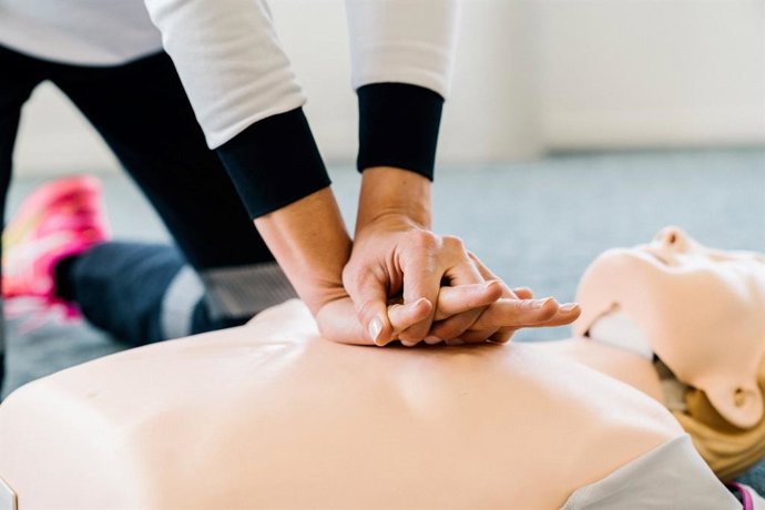 Una mujer practica una maniobra de reanimación cardiopulmonar con un maniquí.
