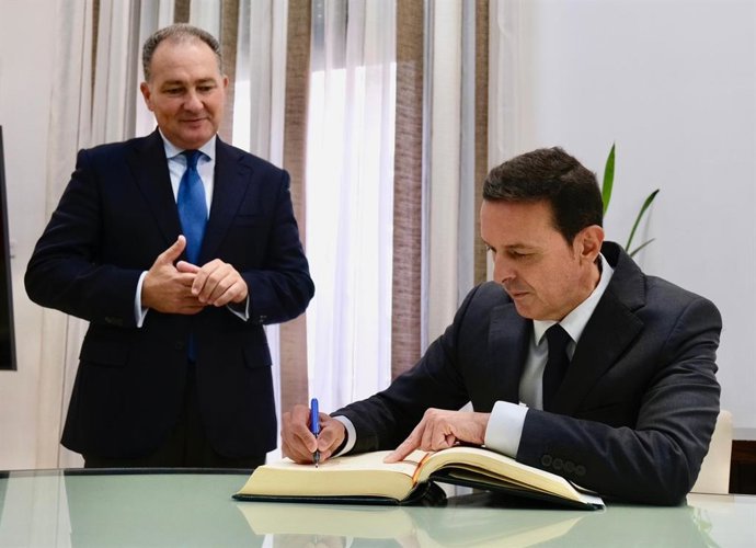 El presidente de la Diputación de Almería, Javier Aureliano García, firma en el libro de honor de la Diputación de Huelva en presencia de su homólogo onubense, David Toscano.