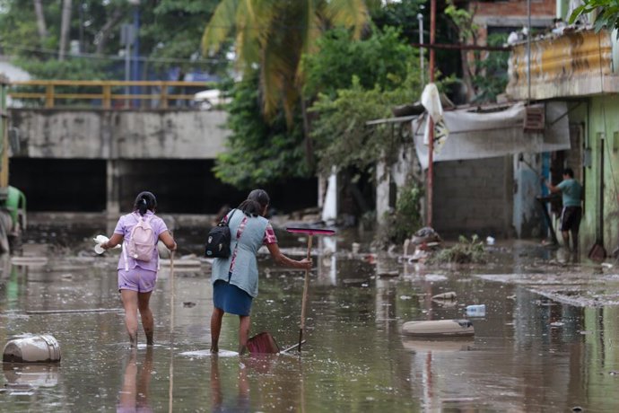 CIDADE DO MÉXICO, 12 de outubro de 2025 -- Pessoas caminham por uma rua inundada na cidade de Poza Rica, estado de Veracruz, México, em 11 de outubro de 2025. Pelo menos 41 pessoas morreram em decorrência das chuvas torrenciais e dos deslizamentos de terr