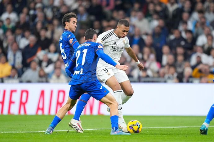 Archivo - El delantero del Real Madrid Kylian Mbappé intenta regatear al defensa del Getafe CF Juan Iglesias en el partido de LaLiga EA Sports 2024-25, en el Santiago Bernabéu.