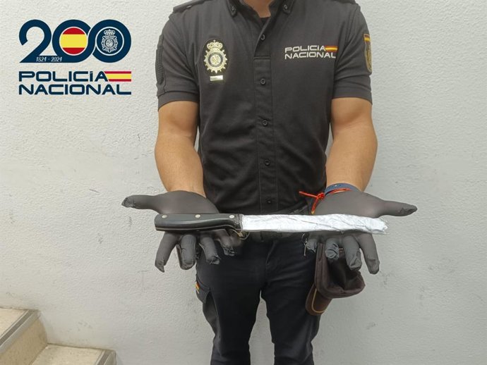 Um policial da Polícia Nacional segura uma faca de cozinha.