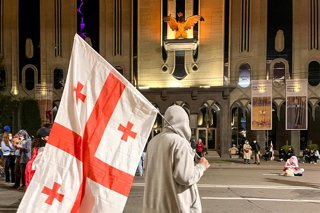 GEORGIA, TBILISI - OCTOBER 5, 2025: A man carries a national flag during a rally outside the Parliament of Georgia. A rally hailed by the opposition as ''a peaceful coup'', took place in Freedom Square on October 4 amid local elections