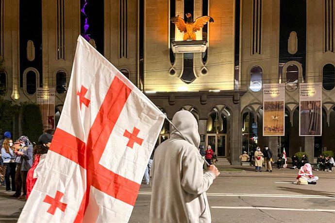 GEORGIA, TBILISI - OCTOBER 5, 2025: A man carries a national flag during a rally outside the Parliament of Georgia. A rally hailed by the opposition as ''a peaceful coup'', took place in Freedom Square on October 4 amid local elections