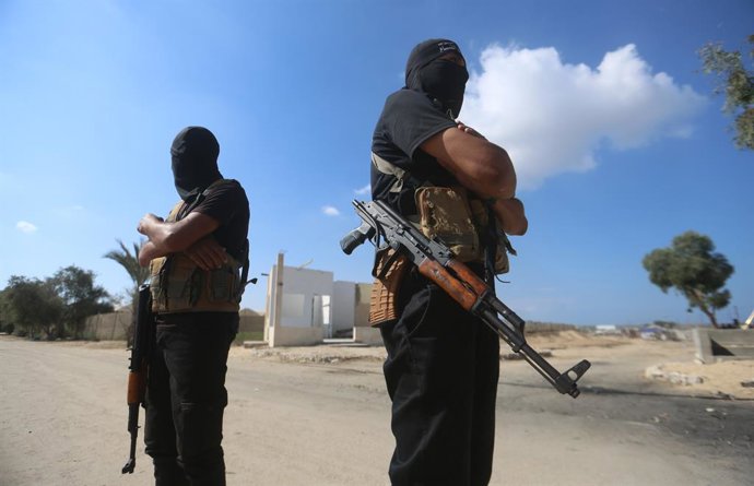 October 13, 2025, Dair El-Balah, Gaza Strip, Palestinian Territory: Palestinian militants of the Ezzedine al-Qassam Brigades, the military wing of Hamas, stand guard next to a crowd watching the transfer of released Israeli hostages to the Red Cross in th