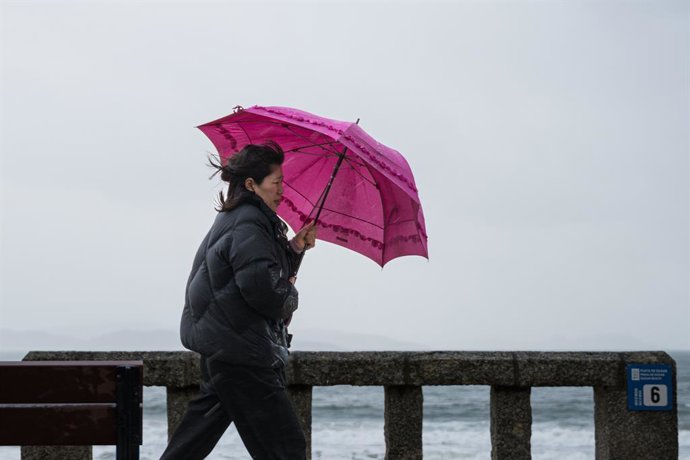 Archivo - Una mujer se refugia de la lluvia con paraguas en la comarca de Salnés, a 27 de enero de 2025, en Salnés, Pontevedra, Galicia (España). La borrasca 'Herminia' recorre la Península hoy y llegará hasta el Mediterráneo y Baleares al final del día c