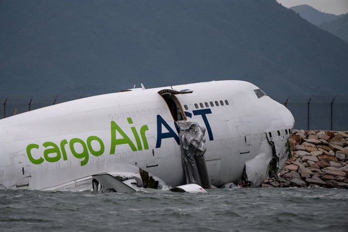 Un avión de carga, parcialmente en el mar después de desviarse de la pista mientras aterrizaba en el Aeropuerto Internacional de Hong Kong