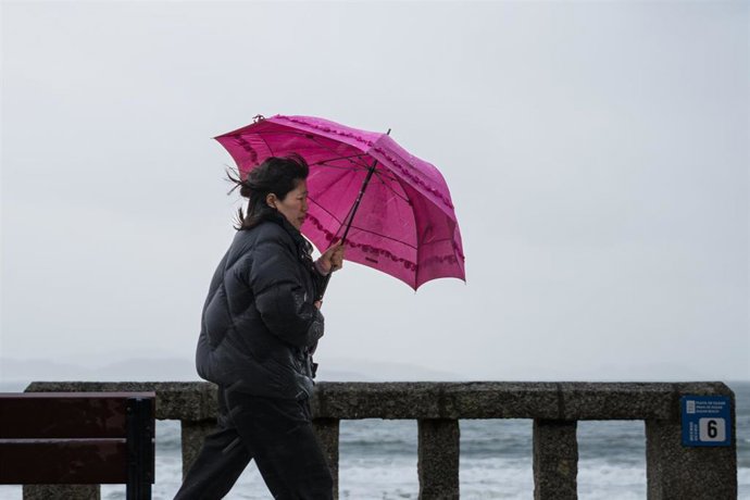 Archivo - Una mujer se refugia de la lluvia con paraguas en la comarca de Salnés, a 27 de enero de 2025, en Salnés, Pontevedra, Galicia (España). La borrasca 'Herminia' recorre la Península hoy y llegará hasta el Mediterráneo y Baleares al final del día c