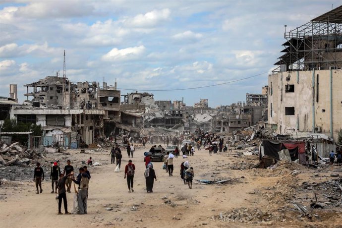 Palestinos caminan entre edificios destruidos por el Ejército de Israel en Jan Yunis tras la entrada en vigor del alto el fuego en la Franja de Gaza (archivo)