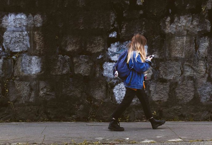 Chica caminando por la calle con el móvil