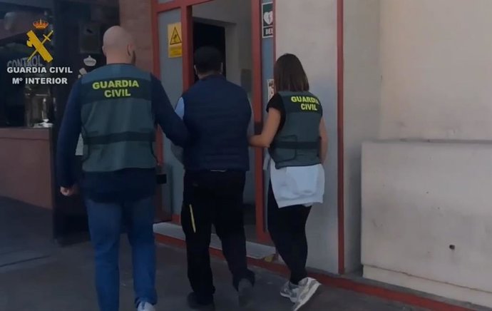 Agentes de la Guardia Civil con uno de los detenidos durante el registro.