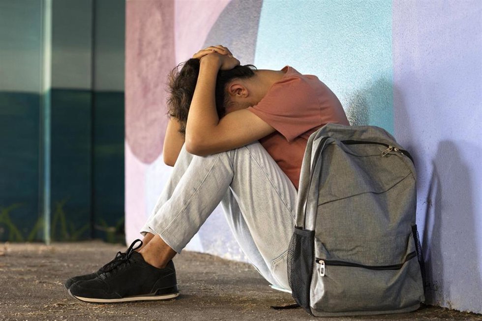 Archivo - Un joven se tapa la cabeza en un centro escolar.