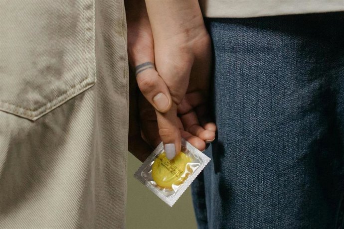Archivo - Imagen de recurso de dos personas con un preservativo en la mano.