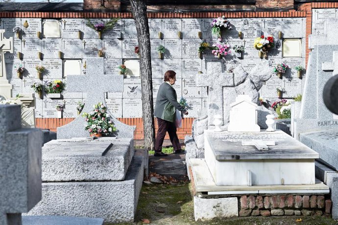 Archivo - Una mujer lleva flores a un ser querido, en el Cementerio de la Almudena