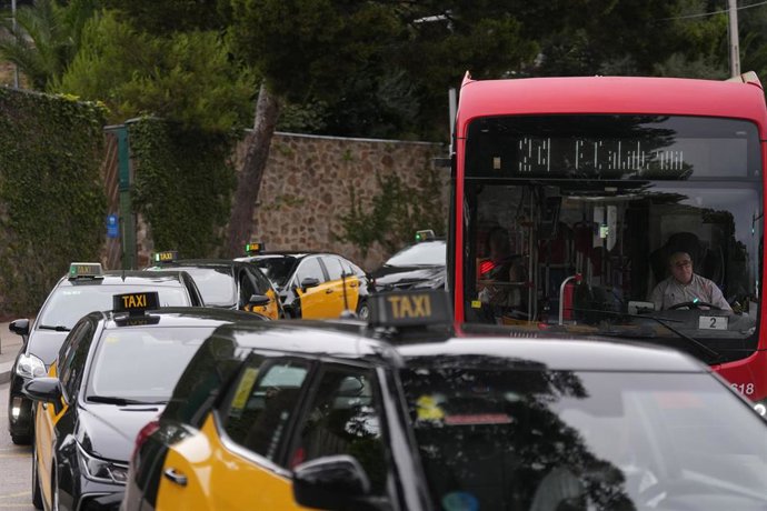 Archivo - Varios taxis y un autobús en una parada de taxis del Park Güell en Barcelona.