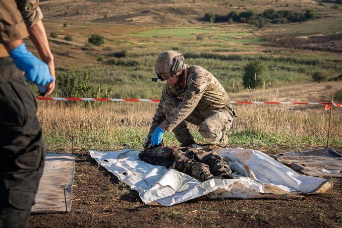Archivo - Uno de los miembros de la ONG ucraniana Platzdam inspecciona el cuerpo de un soldado ruso recuperado de la línea de combate.