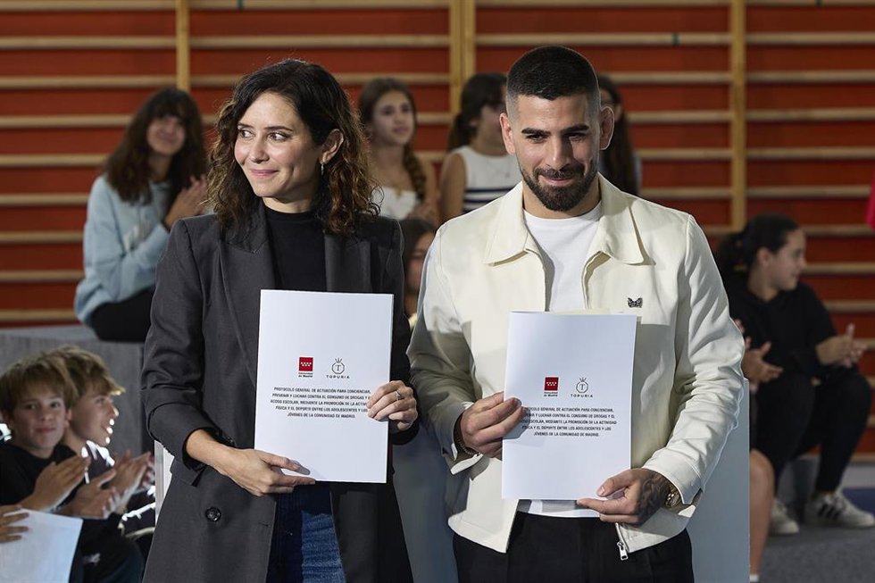 La presidenta de la Comunidad de Madrid, Isabel Díaz Ayuso, y el deportista de de artes marciales mixtas y campeón del mundo de la UFC, Ilia Topuria, durante la firma de un protocolo de colaboración, en el IES Antonio Fraguas 'Forges', en Madrid (España