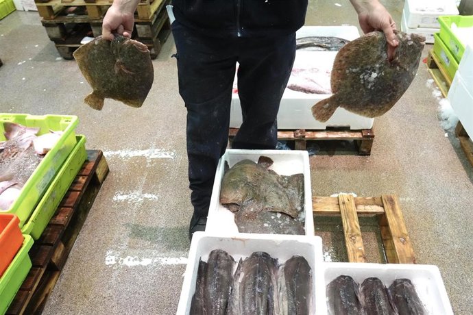 Archivo - Un trabajador sujeta dos lenguados en Mercabilbao.