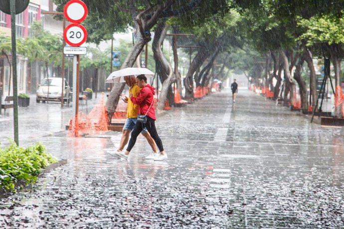 Archivo - Varias personas se cubren de la lluvia con un paraguas mientras caminan por una vía, a 25 de septiembre de 2022, en Las Palmas de Gran Canaria, Canarias (España). El Gobierno de Canarias ha pedido evitar desplazamientos durante este fin de seman