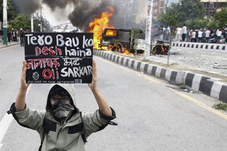 Archivo - September 8, 2025, Kathmandu, Nepal: A young Gen Z protester holds a placard in front of a torched vehicle in Kathmandu, Nepal, on Monday, September 8, 2025. Demonstrators rallied against corruption and the governmentâ€s social media shutdown, w