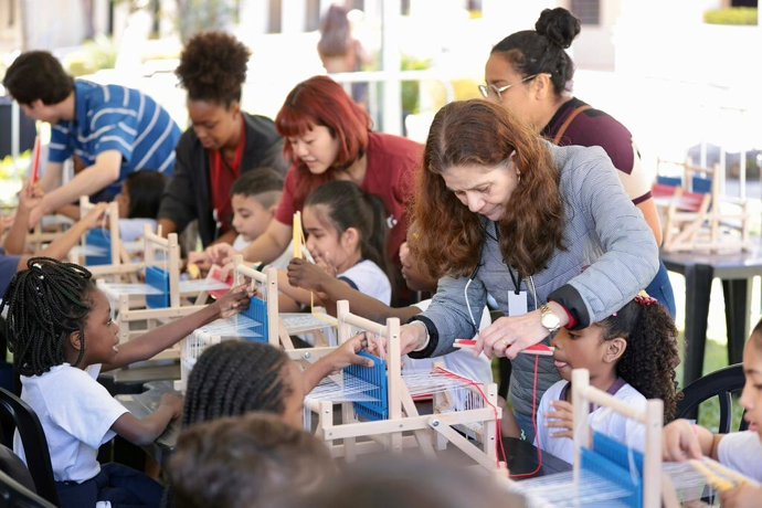Brazilian kids learning how to weave during the exhibition