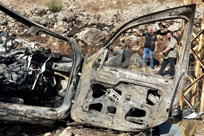 HAROUF, 26 de outubro de 2025 -- Pessoas em frente aos destroços de um carro na cidade de Harouf, perto de Nabatieh, no sul do Líbano, em 25 de outubro de 2025.   Um comandante do Hezbollah foi morto e outra pessoa ficou ferida no sábado em um ataque de d