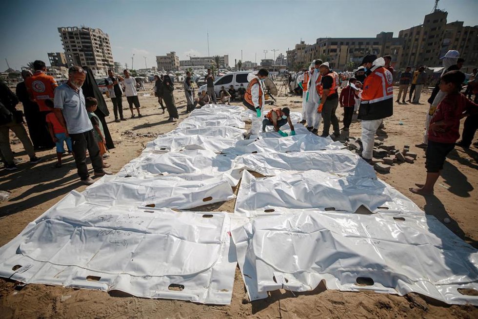 Cadáveres de 60 palestinos recuperados en la ciudad de Gaza en una tumba temporal de cara a su entierro en un cementerio tras el acuerdo de alto el fuego con Israel en la Franja de Gaza