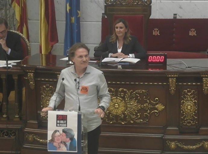 Imagen del pleno del Ayuntamiento de València con la alcaldesa de la ciudad, María José Catalá, en la presidencia y el edil de Compromís Giuseppe Grezzi en el atril con el cartel alusivo a la dana.