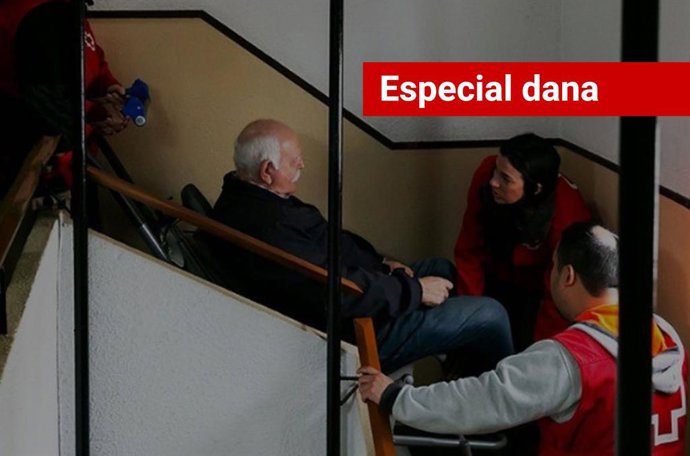 Imagem da assistência da Cruz Vermelha com uma cadeira de lagarta para ajudar um homem com mobilidade reduzida a sair de sua casa em um prédio afetado pelo furacão.
