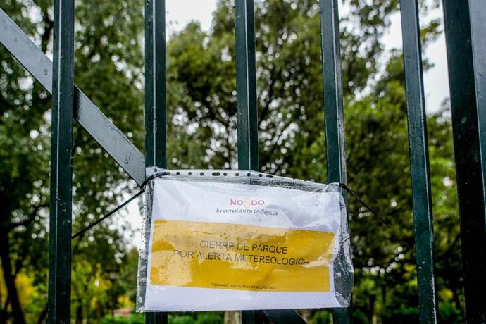 Archivo - Cartel en una reja de entrada al Parque de María Luisa de Sevilla que indica el cierre por alerta meteorológica en octubre de 2023. Imagen de archivo.