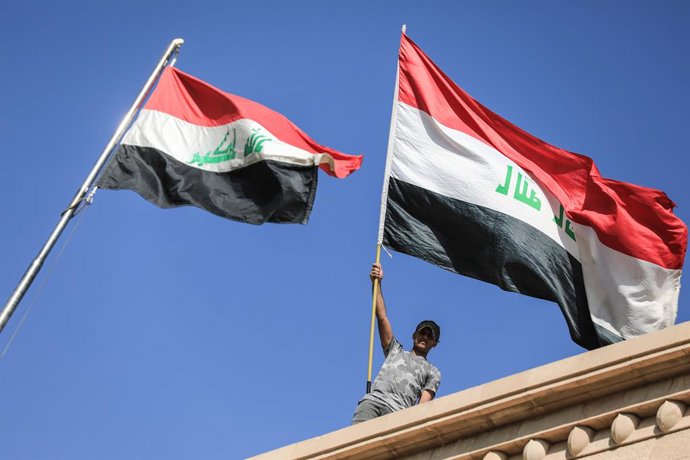 Archivo - 29 August 2022, Iraq, Baghdad: A supporter of Shiite cleric Muqtada Al-Sadr waves a national flag from the roof of the Government Palace during a protest. Followers of al-Sadr headed to the Government Palace and stormed it shortly after the Shii