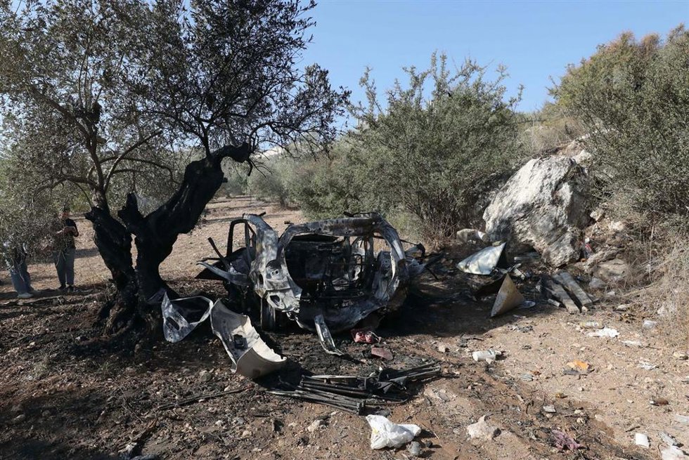 Palestinos observan los restos de un automóvil en el lugar donde las fuerzas israelíes mataron a tres palestinos durante una incursión en la gobernación de Yenín, Cisjordania