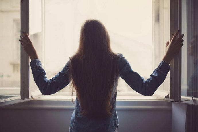 Archivo - Mujer en una ventana durante el Covid