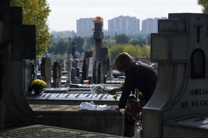 Archivo - Una mujer lleva flores a un ser querido, en el Cementerio de la Almudena.