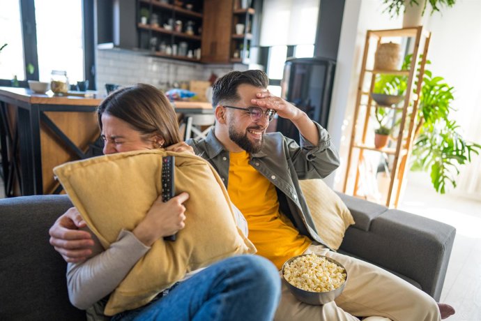 Archivo - Pareja viendo una película en el sofá del salón de su casa.