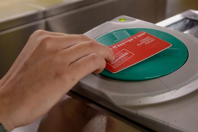 Archivo - Una persona valida su abono en los tornos de entrada al Metro