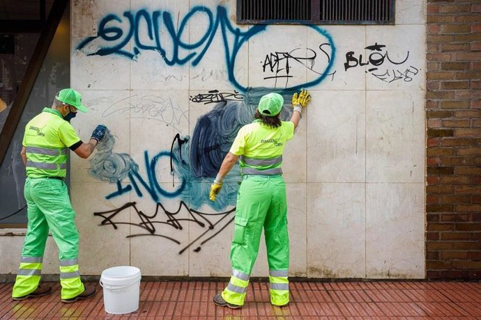 Operarios limpiando una fachada vandalizada con pintadas