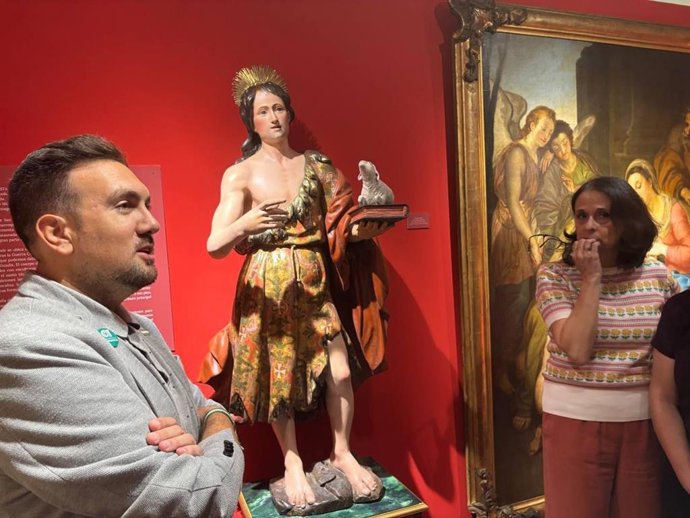 El delegado de Cultura, Patrimonio y Museos de Alcalá de Guadaíra, Christopher Rivas, junto a la talla restaurada de San Juan Bautista del siglo XVII.