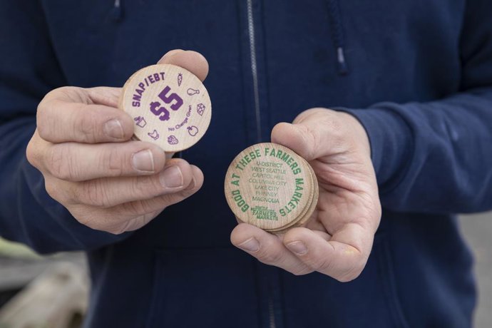 November 2, 2025, Seattle, Washington, U.S: Market manager DYLAN OLSON holds SNAP/EBT benefit tokens at the West Seattle Farmers Market in Seattle on Sunday, November 2, 2025. Customers can use their EBT cards to get tokens to buy SNAP eligible goods, aut