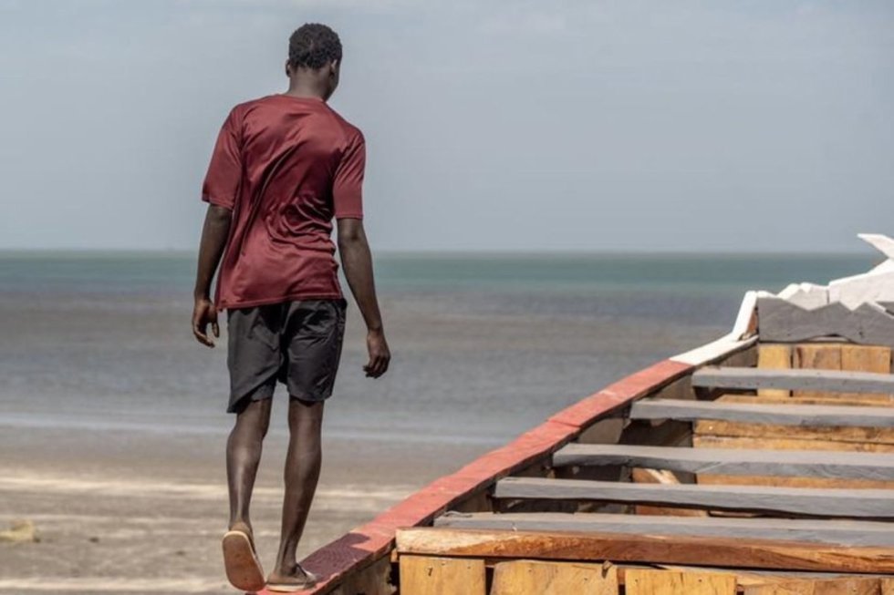 Un hombre camina sobre una barca en la costa de Gambia