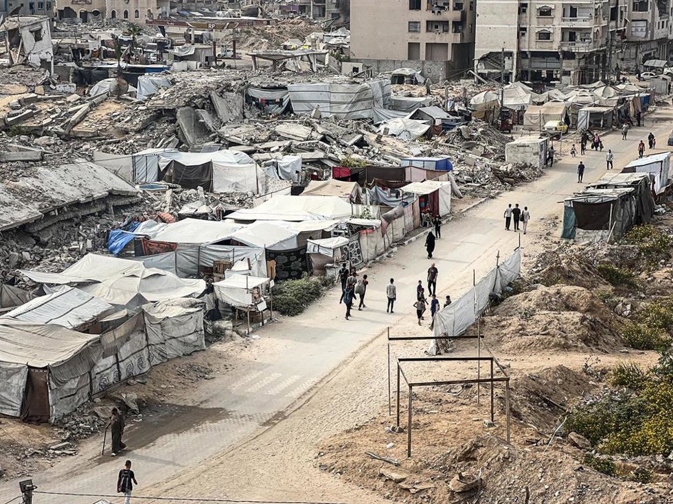 Palestinos en una calle junto a tiendas de campaña para desplazados en la ciudad de Gaza, en medio de los daños causados por la ofensiva de Israel contra la Franja de Gaza (archivo)