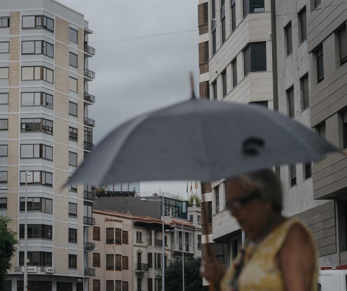 Archivo - Una mujer camina bajo la lluvia en Castelló. Imagen de archivo.