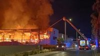 Bomberos trabajan en la extinción de un incendio industrial con llamas muy altas en una nave de Elda (Alicante)