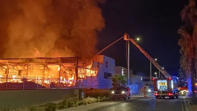 Bomberos del Consorcio de Alicante trabajan en la extinción de un incendio industrial con llamas muy altas en una nave de Elda