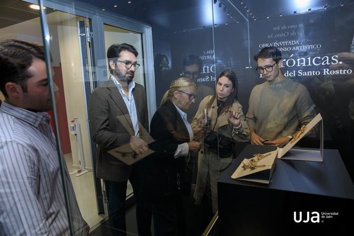 Varias personas observan una de las piezas de la muestra.