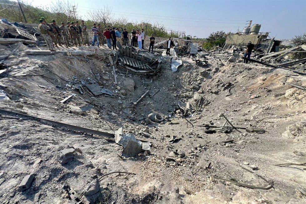 Ciudadanos libaneses y soldados inspeccionan el lugar de un ataque aéreo israelí en la ciudad de Abasiya, Líbano