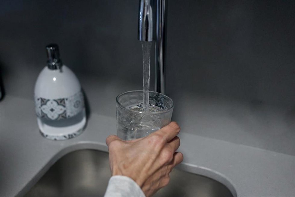 Archivo - Una persona llena un vaso de agua de un grifo