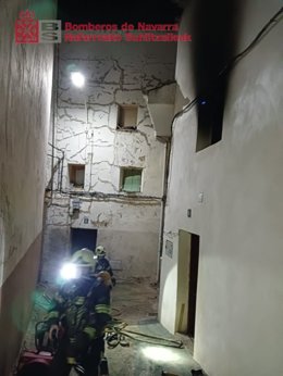 Los bomberos intervienen en la vivienda incendiada.